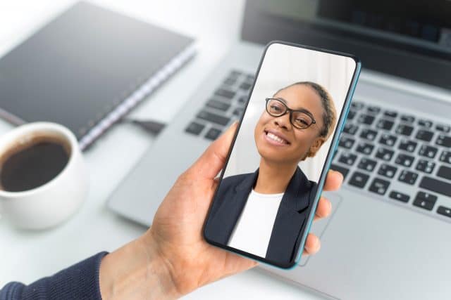 Lächelnde junge Frau auf dem Screen eines Smartphones